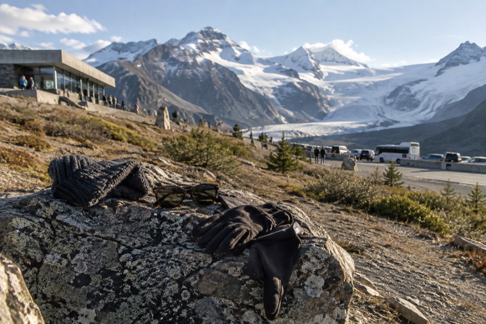 Warm hat, gloves and sunglasses resting on a rock ledge with glacial ice in the background