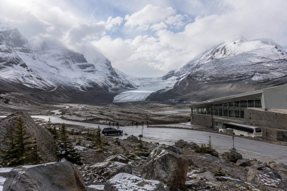 Fresh snow dusting the upper slopes of the Columbia Icefield above bare rock and ice