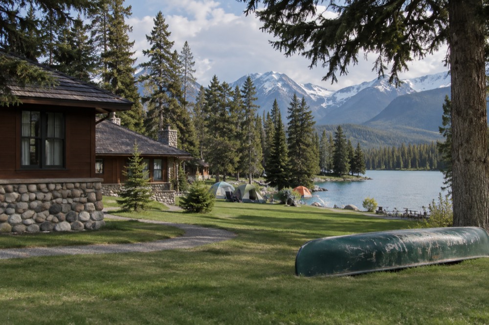 Wooden cabins and tents in a forested campground beside a mountain lake